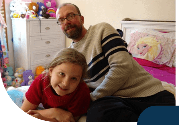 Man and girl smiling in a bedroom with toys.