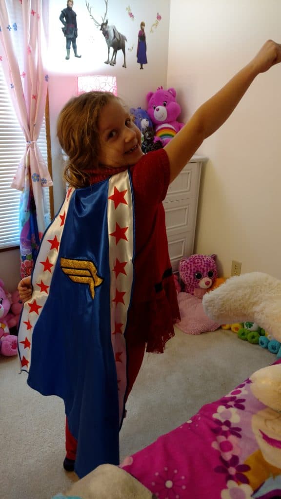 Child in superhero costume posing in colorful room