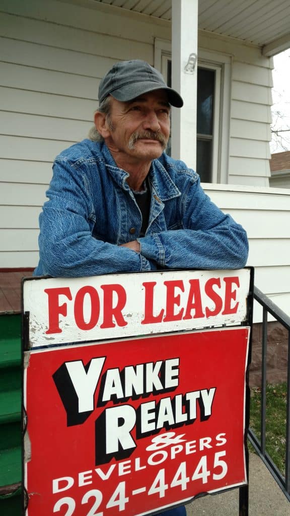 Man standing by 'For Lease' sign