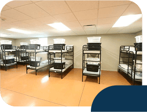 Dormitory room with multiple bunk beds and baskets.