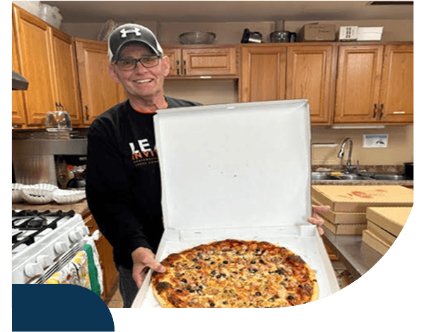 Person holding pizza in kitchen