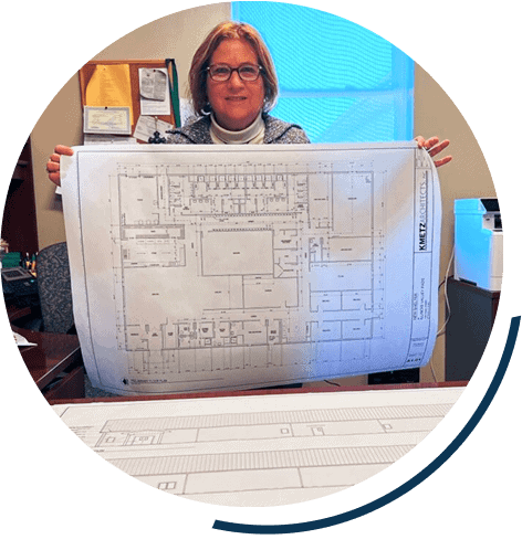 Person holding architectural blueprint in office.