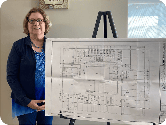 Woman presenting architectural floor plan on easel.